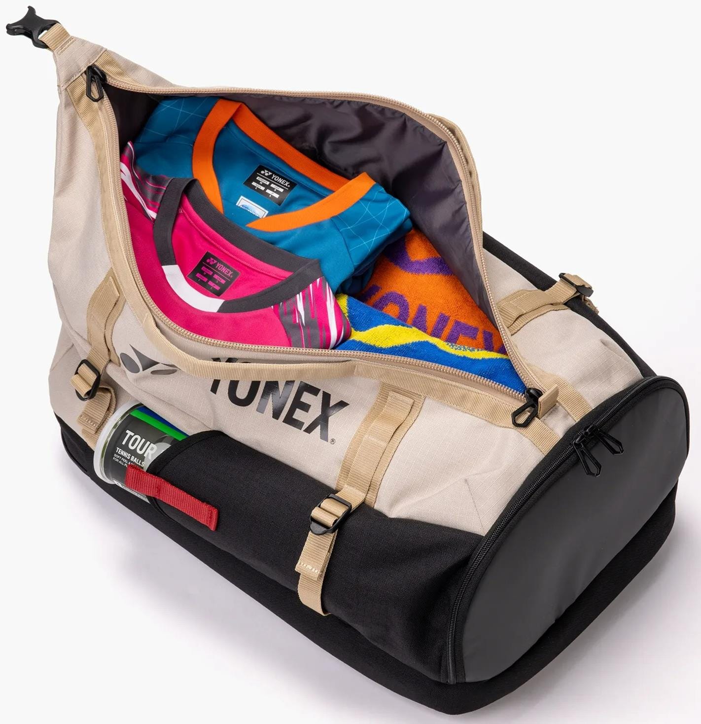 The Yonex BA72612EX Gearlogic Tennis Backpack in beige, ideal as a racket bag, is unzipped to show neatly packed sports shirts and a towel. It features handles, straps, and a "TOUR" label for easy carrying.
