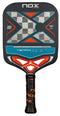 The NOX Luxury Tempo Pickleball Paddle features a black face with a gray and blue checkered "X" design, orange accents, and a NOX-branded grip on the black handle. Made from 18K aluminised carbon fibre for Exclusive Spin technology.