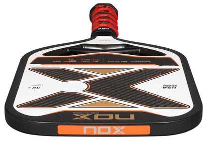 A close-up of the NOX Pro Evo Pickleball Paddle by NOX, showing its black, white, and orange design with carbon fiber details. Enhanced spin and control, plus "Pro Evo" and "USA Pickleball Approved" are visible on the paddle.
