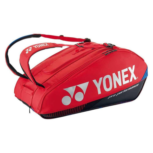 The Yonex 92429EX 9 Racket Pro Tennis Bag in Scarlet features the iconic brand logo and "Pro Performance" printed on it. This bag includes Thermo Guard lining, multiple compartments, and padded shoulder straps for comfortable carrying.