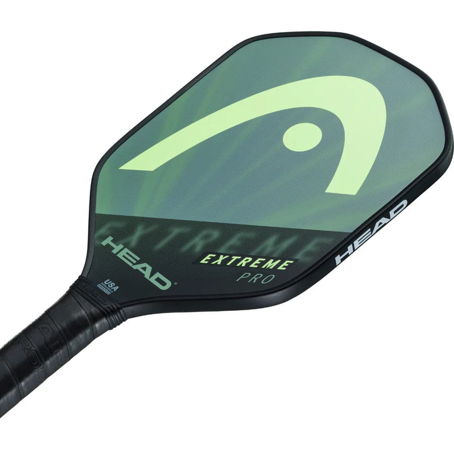A close-up of the HEAD Extreme Pro 2023 Pickleball Paddle shows its black and green design, composite surface, comfort grip, prominent HEAD logo on the face, and “EXTREME PRO” in yellow lettering.