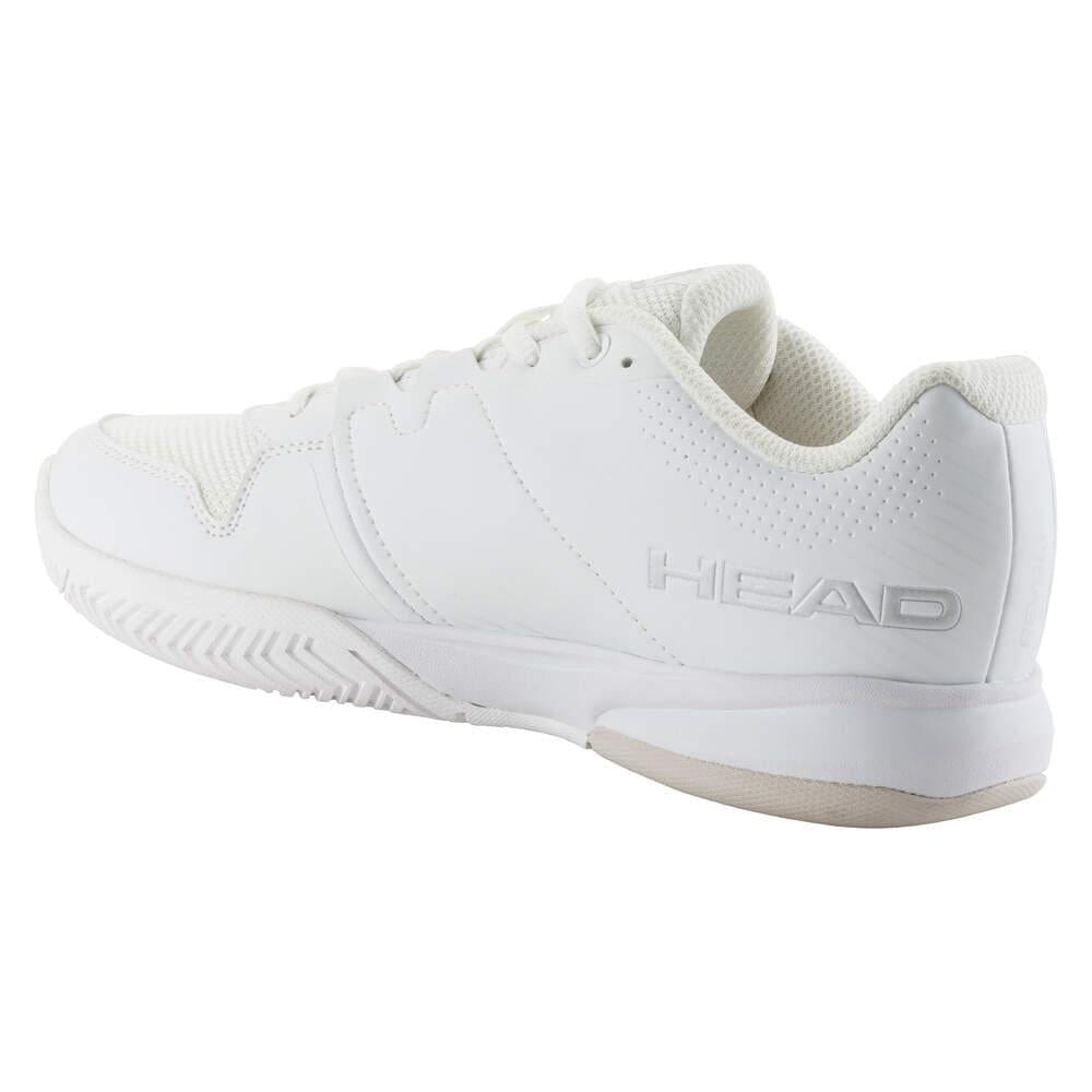 The HEAD Revolt Court Women's 2025 Tennis Shoes in White/Grey feature a textured sole and low-profile design. Their lightweight comfort is ensured by minimal stitching and a padded collar, with "HEAD" prominently displayed on the side.