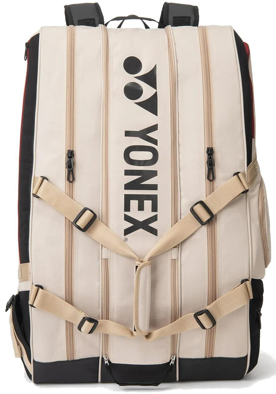The Yonex BA726212EX Gearlogic 12 Racket Tennis Bag in beige features multiple zippered compartments, a black Yonex logo, padded shoulder straps, adjustable beige buckles, and holds up to 12 rackets—perfect for serious players.