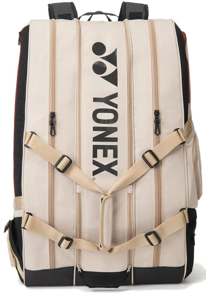 The Yonex BA726212EX Gearlogic 12 Racket Tennis Bag in beige features multiple zippered compartments, a black Yonex logo, padded shoulder straps, adjustable beige buckles, and holds up to 12 rackets—perfect for serious players.