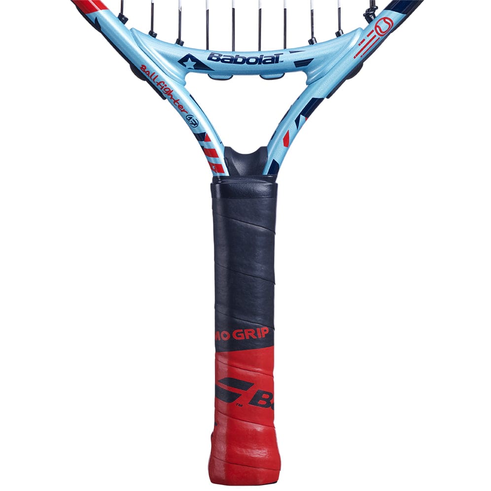 Close-up of a Babolat BallFighter 17 Junior Tennis Racket handle, featuring a red and black teaching grip. The head is visible, displaying strings and a section of the blue frame embellished with logos, perfectly designed to support any young player's tennis journey.