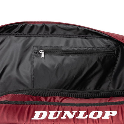 A close-up of an open Dunlop-branded bag reveals a small zippered pocket inside. The black and red exterior combined with its spacious design makes the Dunlop CX Club 10 Tennis Racket Bag both stylish and functional, ideal for any athlete's gear.