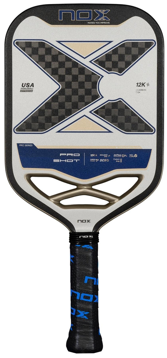 The NOX Pro Shot Pickleball Paddle features a large black and gray X design with blue accents, carbon fibre construction for durability and enhanced spin, and a black and blue grip tape handle. Brand name “NOX” displayed at the top.