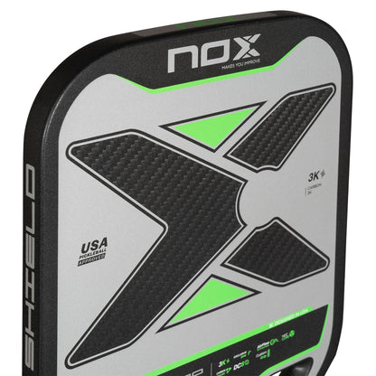 Close-up of the NOX Pro Shield Pickleball Paddle by NOX, showing a bold textured X graphic, green accents, “3K CARBON” text, advanced spin tech, and a “USA Pickleball Approved” label on black and gray.