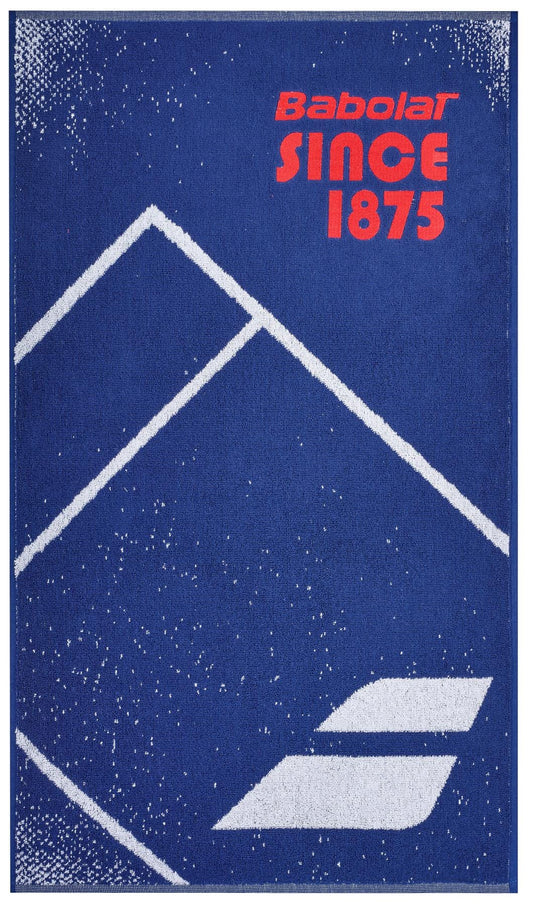 The Babolat Medium Towel - Sodalite Blue, made from 100% cotton, features a vibrant blue background with white geometric mountain shapes and a speckled design. Bold red text at the top proudly displays "Babolat SINCE 1875," while the iconic logo of two diagonal lines is elegantly placed at the bottom, making it an ideal court towel.