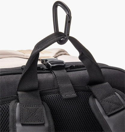 Close-up of Yonex BA72612EX Gearlogic Tennis Backpack in beige, showing its black straps, mesh back panel, and a plastic hook at the top handle for hanging or attaching items.
