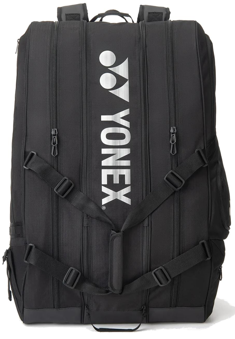 The Yonex BA726212EX Gearlogic 12 Racket Tennis Bag in black features multiple zippers, shoulder straps, and the Yonex logo printed vertically in white. Perfect for serious players needing space for up to 12 rackets.