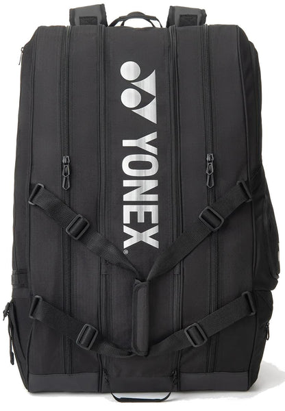 The Yonex BA726212EX Gearlogic 12 Racket Tennis Bag in black features multiple zippers, shoulder straps, and the Yonex logo printed vertically in white. Perfect for serious players needing space for up to 12 rackets.