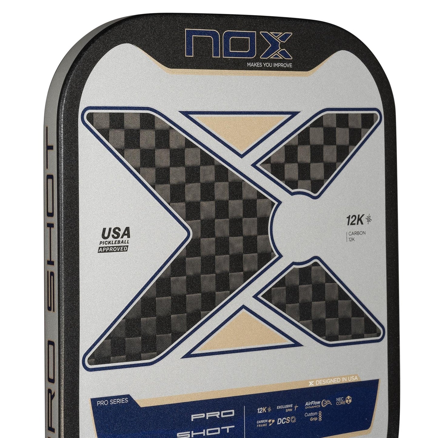 Close-up of the NOX Pro Shot Pickleball Paddle by NOX, showing a bold X design, carbon fiber texture, spin technology features, and “USA Pickleball Approved” text on a silver, black, and blue background.