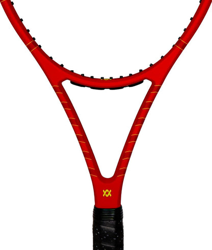A close-up view of the Volkl Vostra V8 315g Tennis Racket in red showcases its distinctive triangular design above the handle, enhancing the Catapult Effect. The brand's yellow logo is prominently displayed near the base. This premium racket is wrapped in black grip tape and is part of Volkl's VOSTRA V8 315g series.