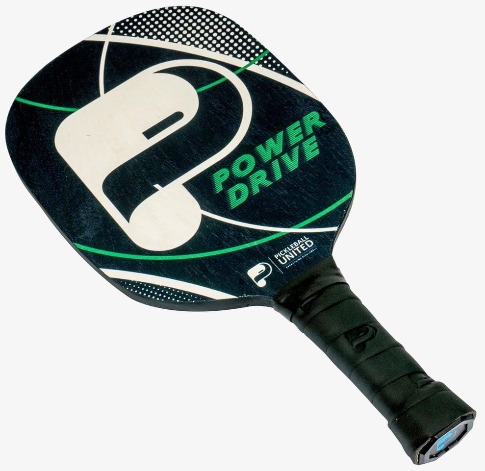 The Pickleball United Power Drive Pickleball Paddle features a black design with green and white "Power Drive" lettering, a large stylized "P," geometric white lines, a cork core for enhanced playability, and a black wrapped handle.