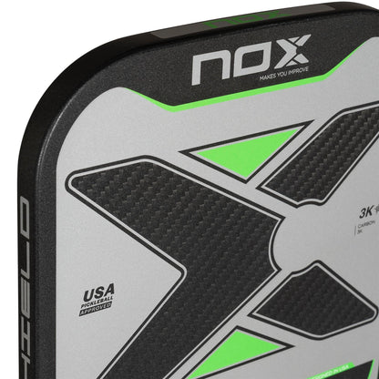 Close-up of the NOX Pro Shield Pickleball Paddle by NOX, showing a bold black “X” with neon green accents, textured carbon fiber surface for spin, and a “USA Pickleball Approved” label on silver.