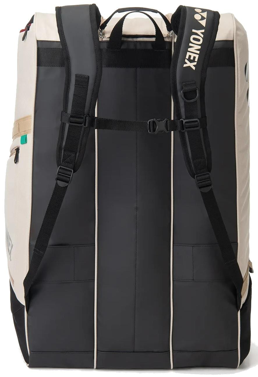The Yonex BA726212EX Gearlogic 12 Racket Tennis Bag in beige, shown from the back, features two padded shoulder straps, a chest strap, a top handle, and the Yonex logo on one strap. Spacious design fits up to 12 rackets.