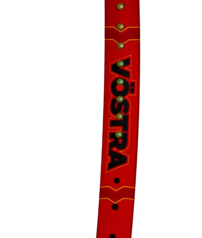 A close-up of a red Volkl Vostra V8 315g tennis racket features the word "Vöstra" in bold, black letters outlined in yellow. The minimalist design is complemented by small circular metal components along the side, enhancing its sleek appearance and adding a hint of the Catapult Effect.