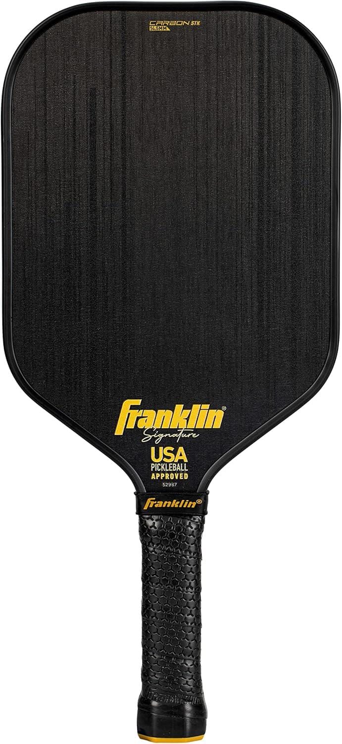 The Franklin Carbon STK 17mm Pickleball Paddle features a black textured surface, yellow "Franklin" logo, "USA Pickleball Approved" text above the black grip, and is officially USAPA approved.