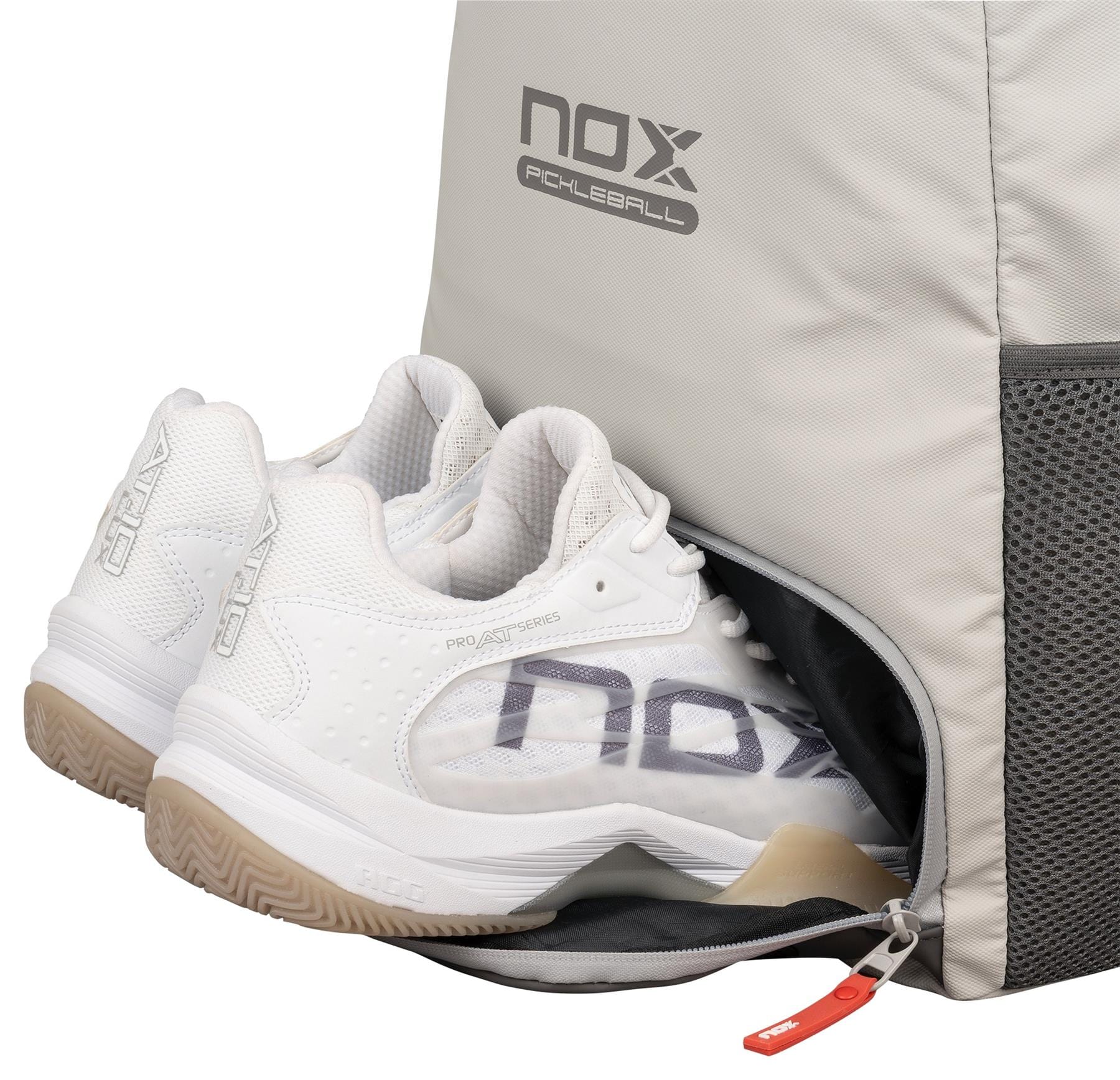 A pair of white athletic shoes partially inside a side compartment of the NOX Supra Pickleball Backpack - Cream, featuring ergonomic padded straps, a mesh pocket, and a visible zipper pull.