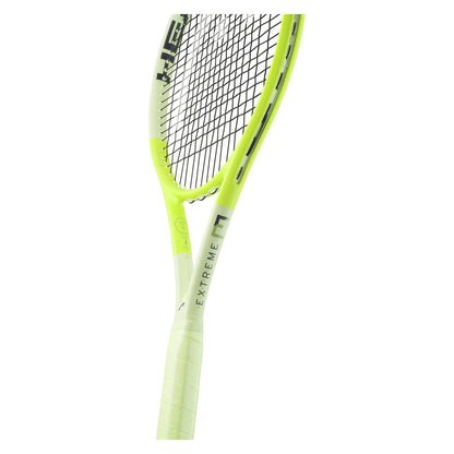 Close-up of a green tennis racket with "EXTREME" printed on the frame, showcasing its HEAD Extreme Elite 2024 design. The white-gripped handle complements the Auxetic 2.0 technology, ensuring extreme spin with tightly strung strings. The image highlights the upper handle and strings, illustrating the innovative features of this HEAD racket.