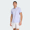 A man wearing an adidas Climacool Mens Tennis Polo Shirt in Violet Tone and white shorts stands against a plain light background, smiling at the camera.