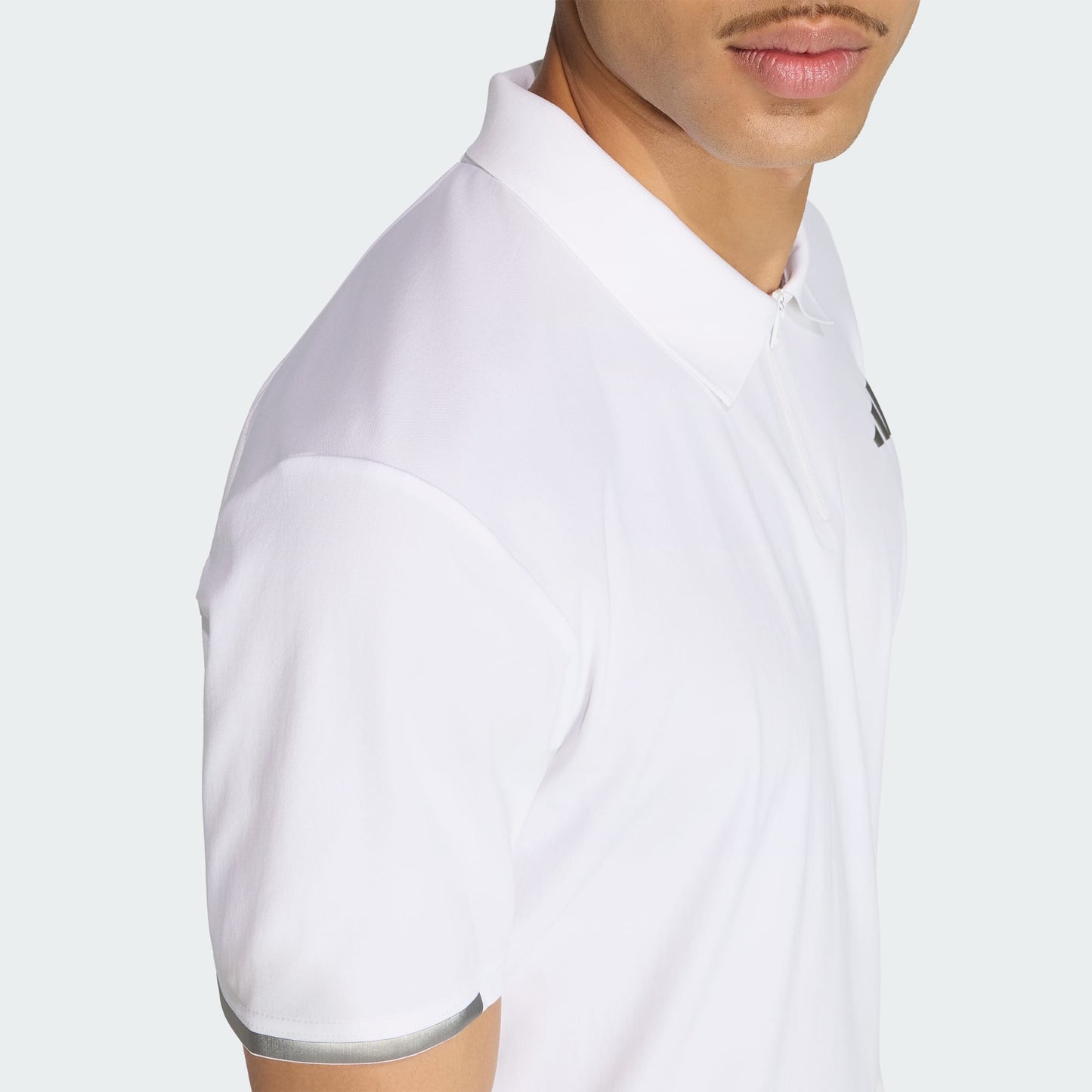 A man wearing the adidas Climacool Mens Tennis Polo Shirt in white, featuring a subtle chest logo and silver sleeve accent, is shown from the torso up against a light background.