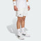 A person wearing adidas Climacool Mens Tennis Shorts in white, paired with white socks, wristbands, and black-accented white adidas sneakers, stands against a plain light background.