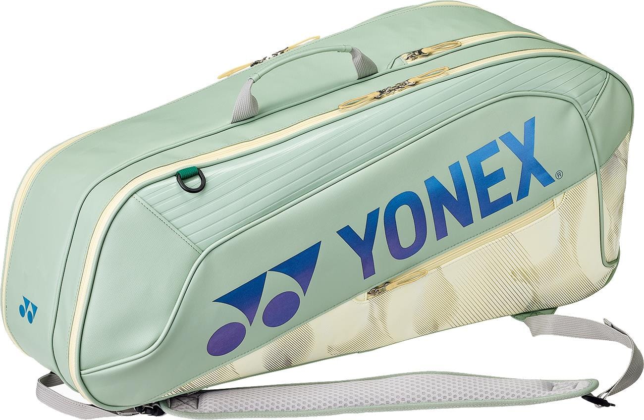 The Yonex 02626EX Expert 6 Racket Tennis Bag in smoke green features the Yonex logo and name in blue, a handle, shoulder strap, multiple zippered compartments, and dedicated racket storage to keep your gear organized.