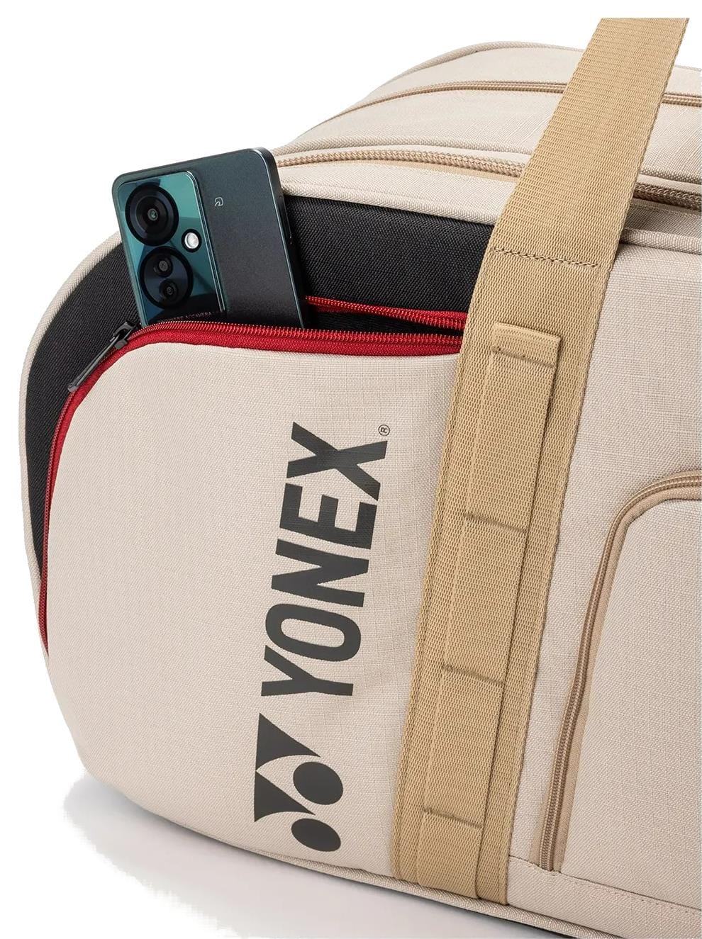 The Yonex BA72631WEX Gearlogic Tournament Tennis Bag in beige features a tan strap and a front pocket, seen here partially unzipped to reveal a black and green smartphone. The Yonex logo stands out, ideal for tournament play.