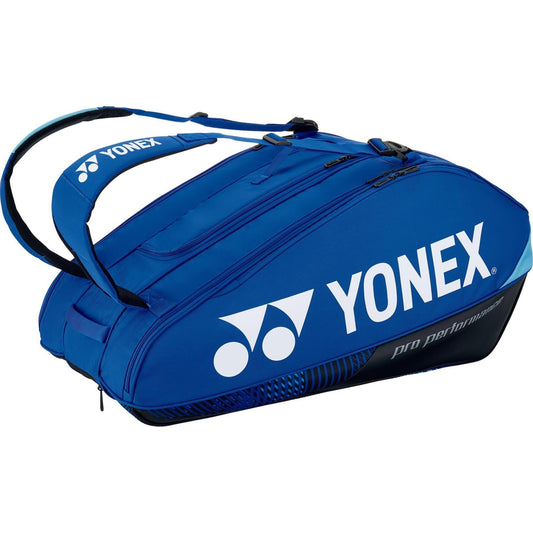 The Yonex 92429EX 9 Racket Pro Tennis Bag, in a stylish cobalt blue color, prominently displays the "YONEX" brand name in white. It features Thermo Guard lining and includes two adjustable straps along with several zippered compartments, providing an ideal solution for securely transporting your tennis gear.