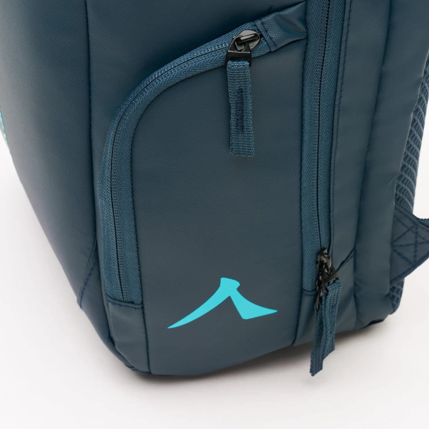 Close-up of the Kanso Intuko Tennis 23L Backpack in navy, your everyday companion. It features a light blue logo resembling an abstract mountain or "A," with visible zippers and stitching details, plus a separate compartment. The background is white.