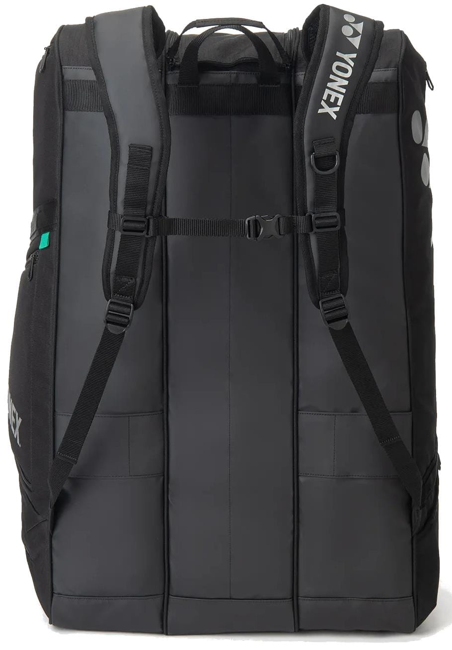 The Yonex BA726212EX Gearlogic 12 Racket Tennis Bag in black features padded shoulder straps, a chest strap, and side pockets for sports gear. The Yonex logo appears on the shoulder strap.