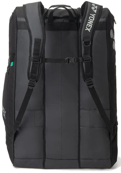 The Yonex BA726212EX Gearlogic 12 Racket Tennis Bag in black features padded shoulder straps, a chest strap, and side pockets for sports gear. The Yonex logo appears on the shoulder strap.