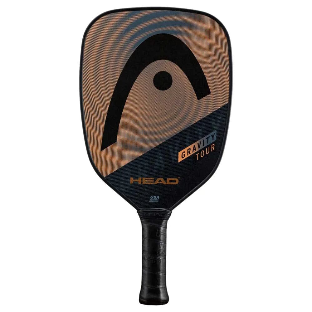 The HEAD Gravity Tour 2023 Pickleball Paddle by HEAD features a black and copper design, large logo, and black handle. Its Hybrid Hitting Surface and SpinOn tech boost control and spin, with "Gravity Tour" and "HEAD" on the face.