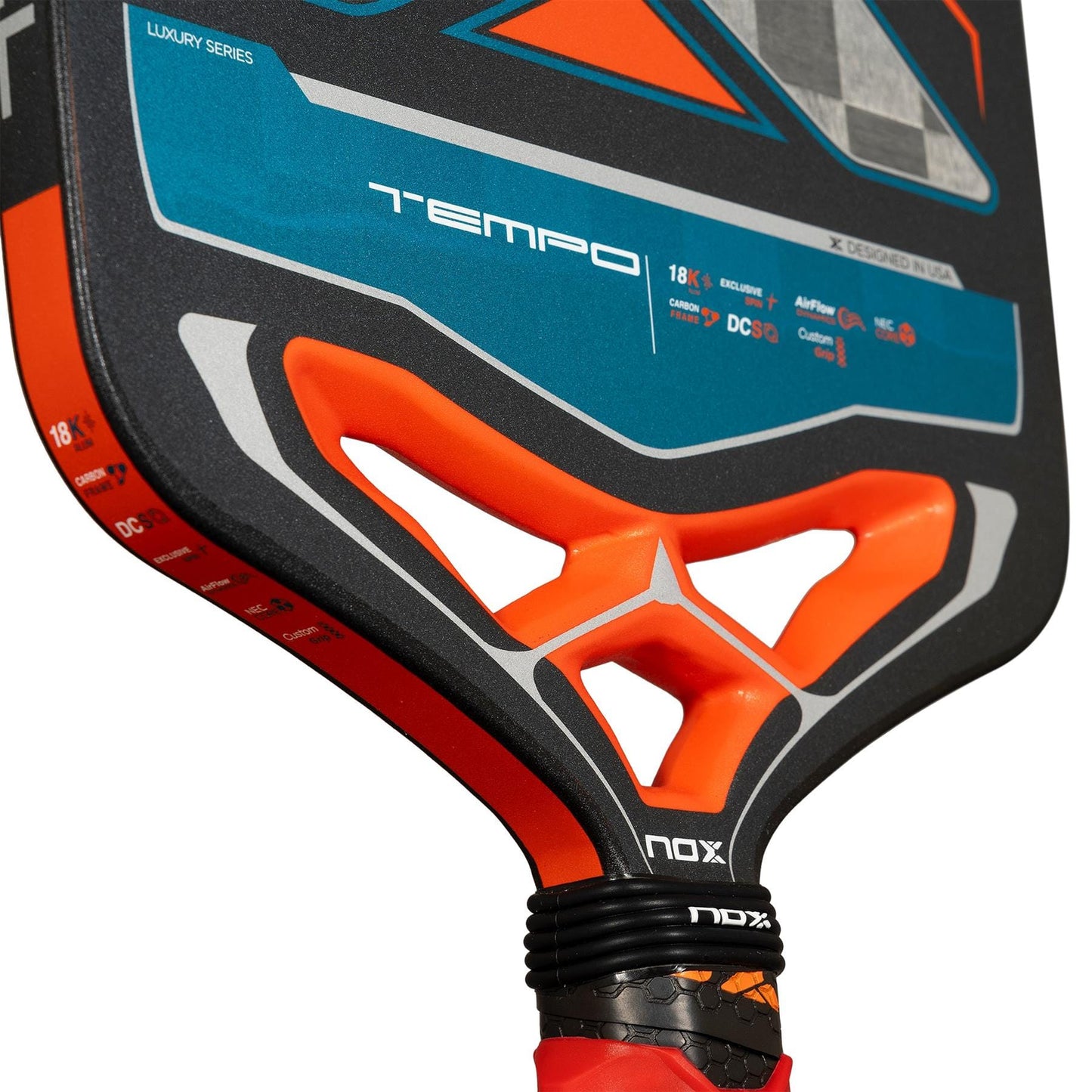 Close-up of the NOX Luxury Tempo Pickleball Paddle, featuring a blue and orange face with "TEMPO" lettering, black NOX grip, angular throat cutouts, and durable 18K aluminised carbon fibre construction.