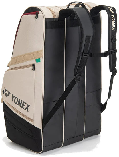 The Yonex BA726212EX Gearlogic 12 Racket Tennis Bag in beige features multiple compartments, shoulder straps, a side pocket, self-standing design, and prominent Yonex branding. Holds up to 12 rackets for ultimate convenience.