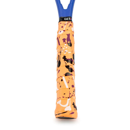 A close-up of the Get A Grip Hot Mess Tennis Overgrip - Orange showcases a vibrant abstract pattern with splashes of orange, purple, black, and white. Made from premium materials, its textured design ensures a secure, non-slip hold. The upper end prominently displays the brand name "Get A Grip.
