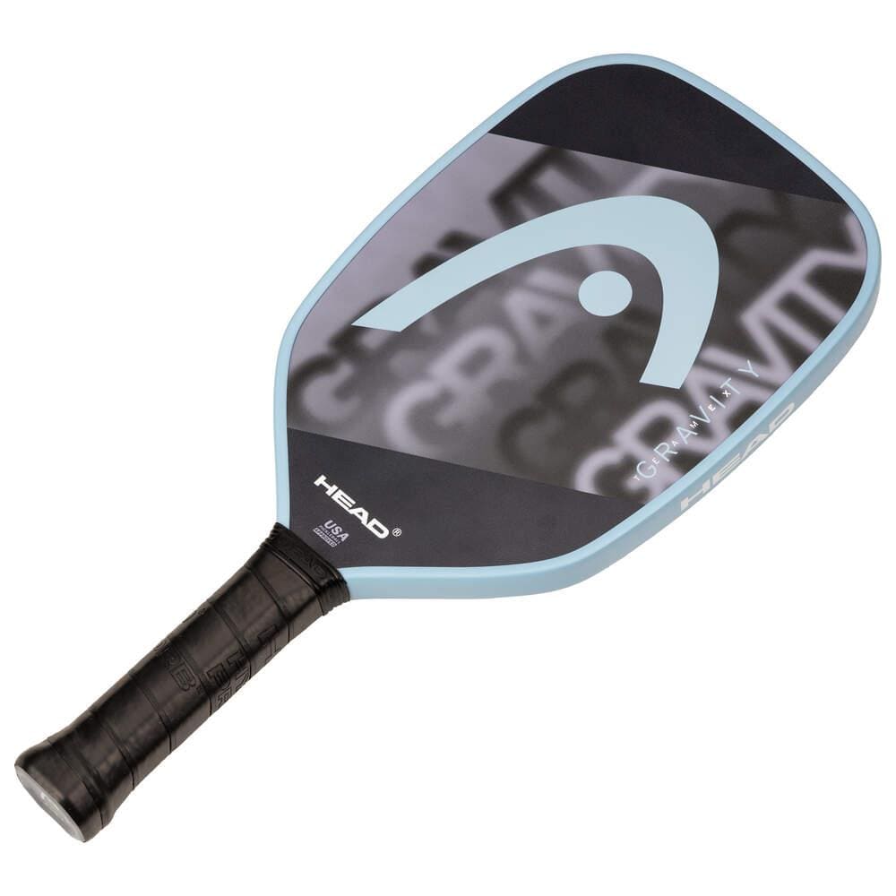 The HEAD Gravity Team EX 2025 Pickleball Paddle features a black and gray face with a large white logo, light blue edge, and black grip tape for excellent control and precise shots on the court.