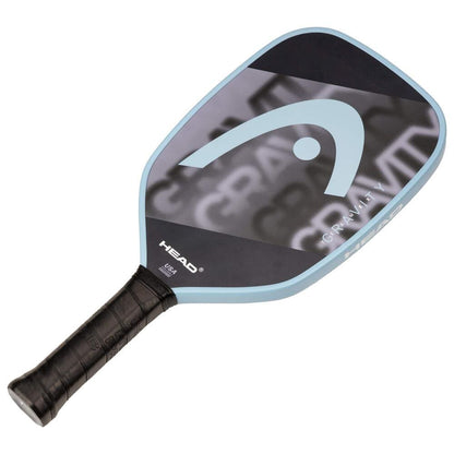 The HEAD Gravity Team EX 2025 Pickleball Paddle features a black and gray face with a large white logo, light blue edge, and black grip tape for excellent control and precise shots on the court.