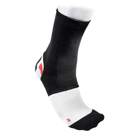 A close-up of a foot showcasing the McDavid 2-Way Elastic Ankle Sleeve in black and white, crafted by McDavid for optimal support and compression. The breathable sleeve snugly fits over the ankle and part of the foot, with a white sock peeking out underneath.