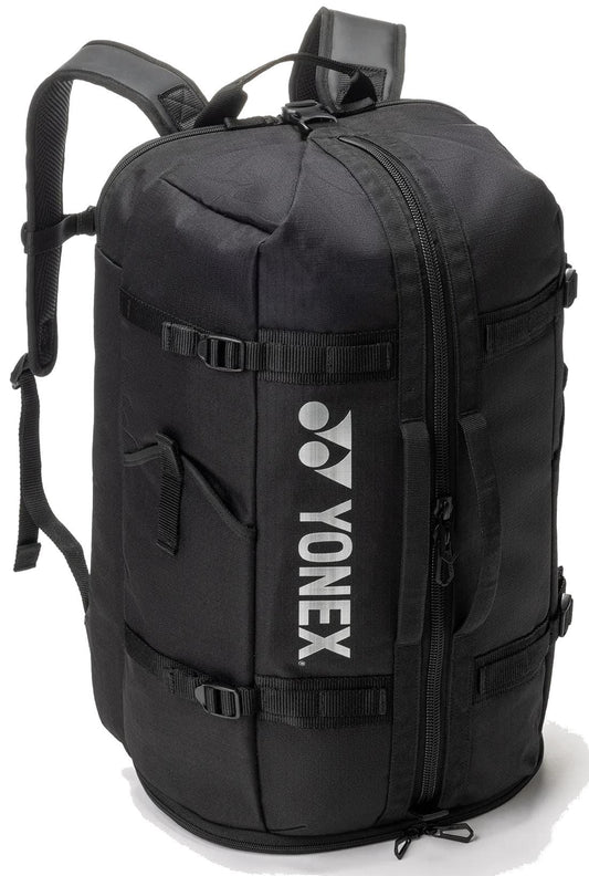 The Yonex BA72612EX Gearlogic Tennis Backpack in black features backpack straps, side handles, a vertical white Yonex logo, cylindrical shape, 40L capacity, and multiple zipper compartments for organized gear storage.