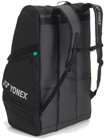 The Yonex BA726212EX Gearlogic 12 Racket Tennis Bag in black features two padded shoulder straps, side pockets, a white Yonex logo on the front pocket, multiple compartments, and a sleek modern design.