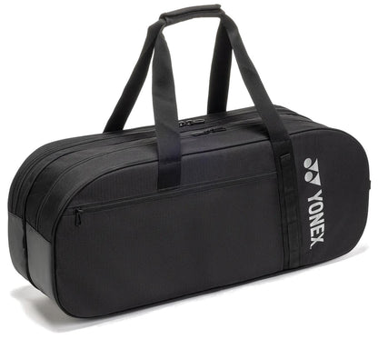 The Yonex BA72631WEX Gearlogic Tournament Tennis Bag in black features two handles, a shoulder strap, and a front zippered pocket. The white Yonex logo on the side adds style—ideal for carrying all your tennis gear.