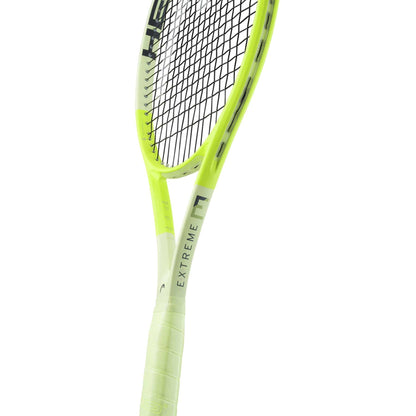 A close-up of the HEAD Extreme Pro 2024 Tennis Racket in neon yellow and black, showcasing "EXTREME" on the frame, with focus on its handle, throat, and stringed head designed for advanced spin.
