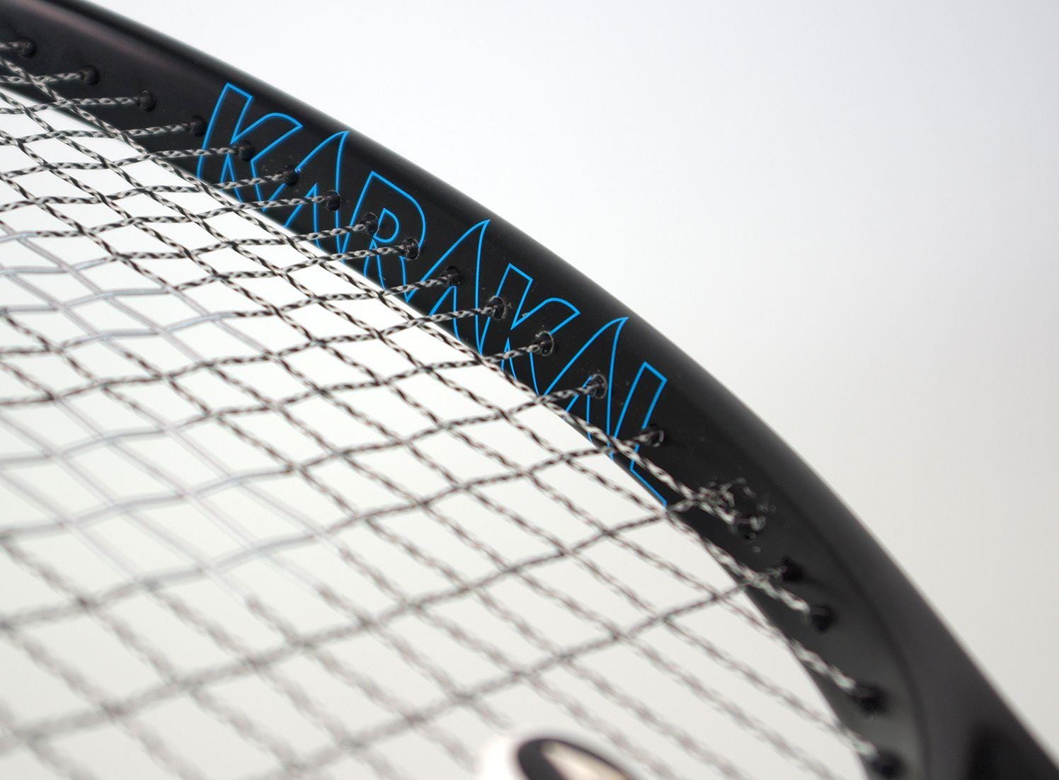 Close-up of the Karakal Graphite Lite 260 Tennis Racket's strings and frame, featuring the brand name in a stylish black and blue design. The tightly woven strings emphasize this lightweight racket's precision, with its Fast Fibre Nano Graphite Gel enhancing performance against a plain backdrop.
